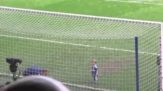 Stadium cheers as two-year-old son of Chelsea FC's goalie scores a goal.