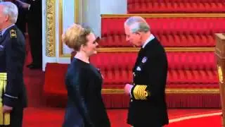 Adele recibe su MBE a manos del Príncipe Carlos.