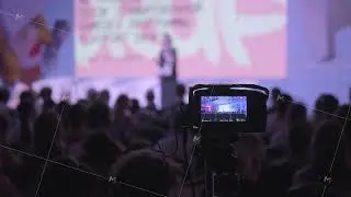 Camera recording a live conference with audience in the background