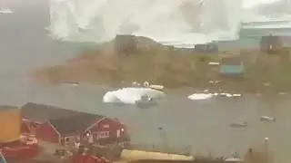A huge iceberg is looming over a village in Greenland