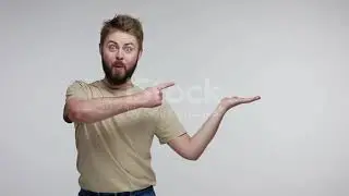 Surprised Bearded Guy Pointing Aside Holding Empty Space On Palm And Looking With Open Mouth Amazed