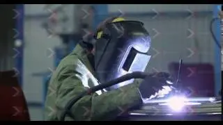 A welder in a mask and overalls at work