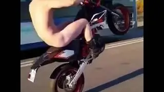 Naked man on motorcycle pops wheelie in broad daylight