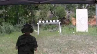 12 year old shooting a .22 pistol at a plate rack