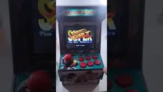 Mini arcade game console with SEGA games playing Super Street Fighter II. Lights up and everything
