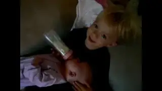 Toddler feeding his baby sister a bottle early in the morning