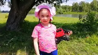 Ярослава управляет  машинкой на пульте управлении off road на природе.