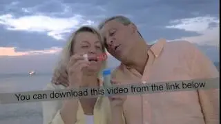 Senior couple blowing bubbles at the seaside