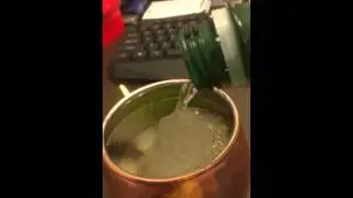 Pouring ice cold water on top of an ice cube in a copper mug.