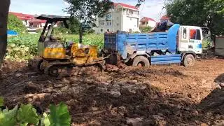 The truck is stuck helping by bulldozer