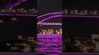 The harbor lights of Sydney Australia, including projections on the Harbor Bridge and Opera House.