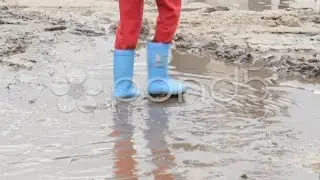 Child feet walk on puddle dirt, blue boots, children unsafety, click for HD. Stock Footage