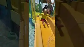 Милый ребенок на горке. Малыш Дэвид развлекается в аквапарке
