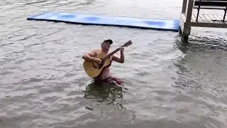 Man playing the guitar while peeing in the water