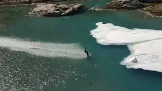 Guy Skis Down Glacier and Skims Across Lake - 990171