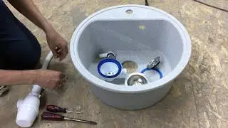 Installing a siphon with a round overflow on a porcelain stoneware sink in the kitchen.