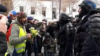 Gilets Jaunes protester offering flowers to the riot police