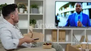 Man Eating Fries and Watching TV in the Living Room | Stock Footage - Envato elements