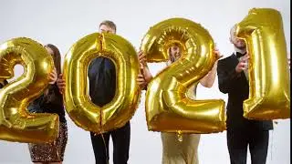 Happy New Year young men and women turning towards camera and showing number 2021 golden ballo