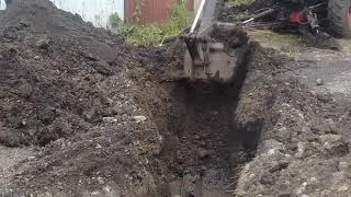 Экскаватор ЮМЗ в работе,копает траншею для трубы.