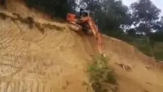 Эскаватор сходит с крутого холма