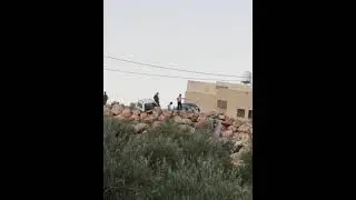 מתנחל מכוון נשק לעבר בתי הכפר קרוואת בני חסן כשלצדו חיילים, 2 בדצמבר 2023