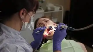 Dentist polishing and varnishing a girl's teeth