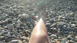 woman laying on the beach, female legs relaxing on seaside sunset, pov