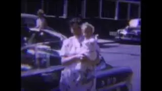 1950s Mom holding baby by vintage car