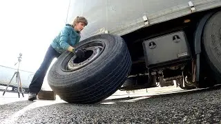 Young female truck driver changing a flat tire
