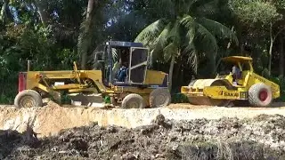 Motor Grader, Vibro Sakai, Mini Excavator and Dump Trucks Busy Working On Road Construction