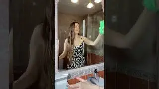 Симпатичная девушка моет зеркало.