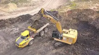 Экскаватор Cat 374F L грузит вскрышей самосвалы Volvo A40G - drone video