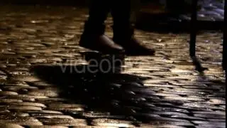 Feet of Several People Walking Along a Cobblestone Sideway at Night in Slo-Mo