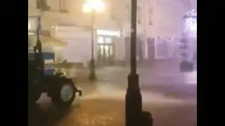 Трактор моет дорогу во время ливня в Москве
