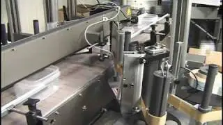PS Labeler applying front and back labels on empty tub, slightly oval,