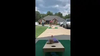 Girl Lays On The Cornhole Board While A Guy Makes The Shots