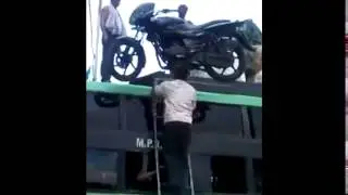 AMAZING! Indian man balances motorcycle on head to climb a ladder and get it tot he top of a bus.