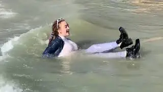 Olga in boots, sports trousers in a white sweater in the sea