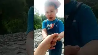 Little boy playing near river in sunny day. Happy childhood and children activities.