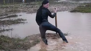 Девушка в сапогах на высоких каблуках в глубокой глине и воде