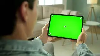 man using green screen tablet in neutral living room