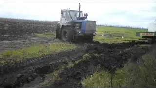 т150 тянет телегу с удобрением по полю  Грязь