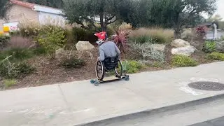 Evan Lalanne in his wheelchair riding an electric skateboard with traffic