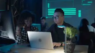 Colleagues collaborating atlaptop in modern office
